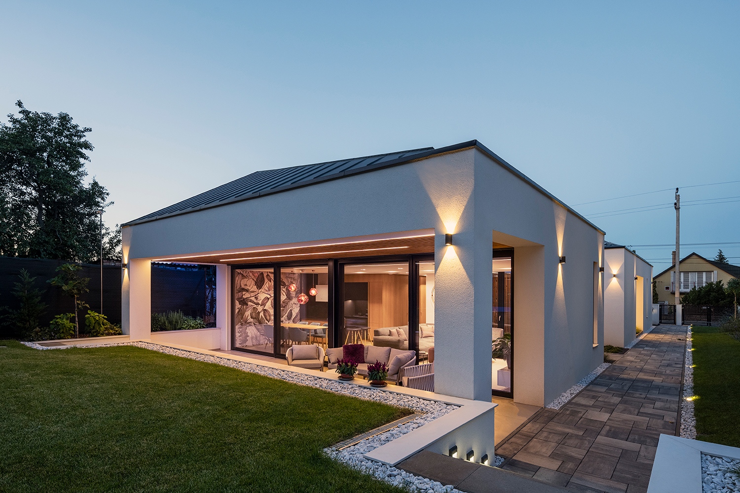 Az épület hátsó kert felé nyílik meg, így a zöld látványa és a beáramló fény is a kompozíció részévé válik